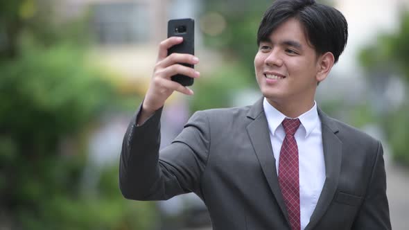 Young Handsome Asian Businessman Using Phone in the Streets Outdoors alt