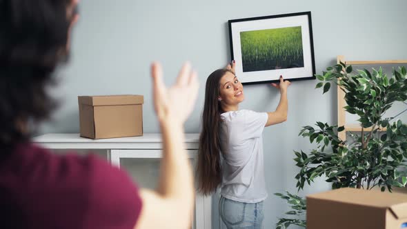 Husband and Wife Picking Place for Picture in New House Talking and Gesturing alt