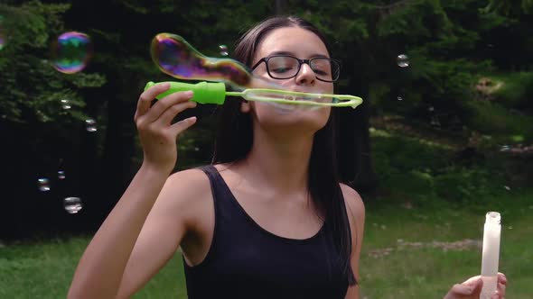 Teenage Girl Blowing Soap Bubbles in Summer