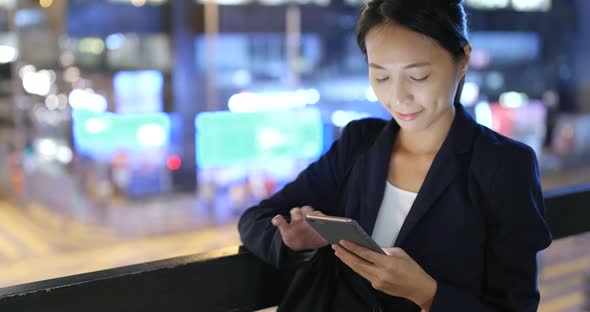 Woman Using cellphone with the background of Hong Kong city  alt