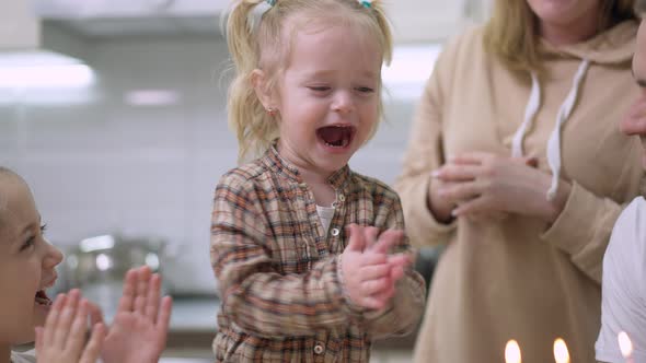 Portrait of Excited Baby Girl Clapping and Laughing Blowing Candles on Birthday Cake alt