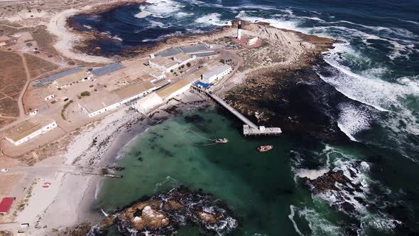 Aerial arc shows Fryer's Cove, lighthouse, Doringbaai fishing village; RSA alt