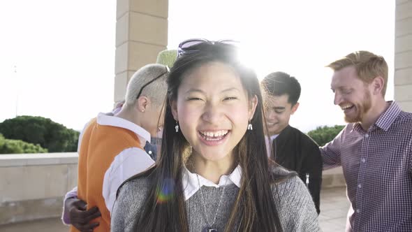 Asian woman smiling at camera hanging out with friends