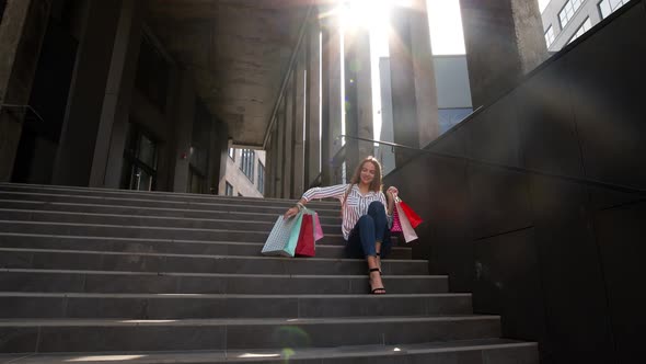 Cheerful Girl Walking From Centre Mall with Shopping Bags, Happy with Purchase on Black Friday alt