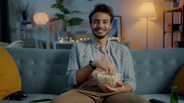 человек смеется у телевизора с попкорном