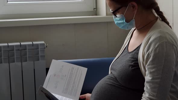 Young Pregnant Woman In Medicine Protective Mask Reading On Couch Waiting For Appointment Medical