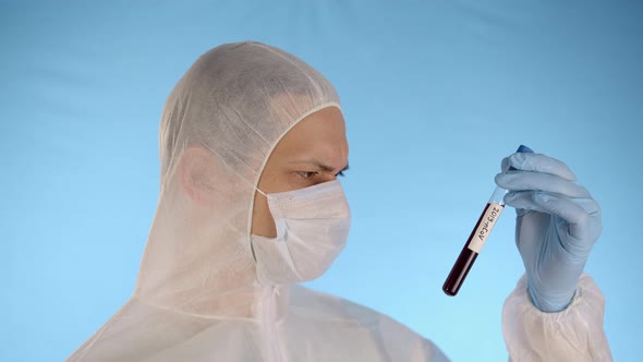 Man in Protective Suit Mask Gloves Holds in Hands Test Tube with Coronovirus