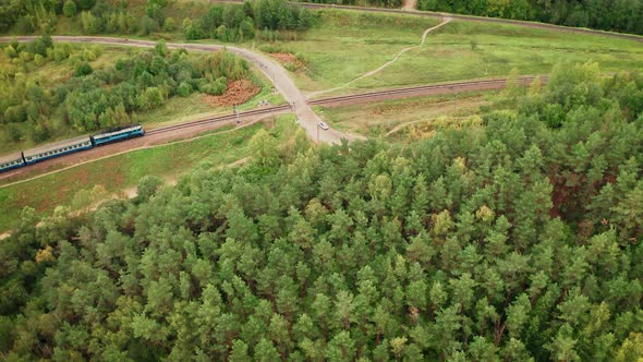 Aerial View Of Railway With Passenger Train Among Green Forest In Wild Nature