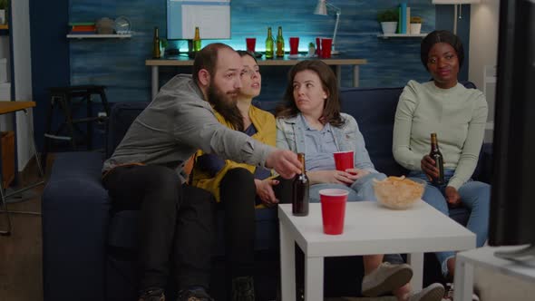 Multiracial Friends Sitting on Couch Watching Fun Movie on Television During Home Party alt