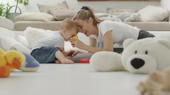 Happy and smiling mom makes her beautiful baby drink orange juice alt