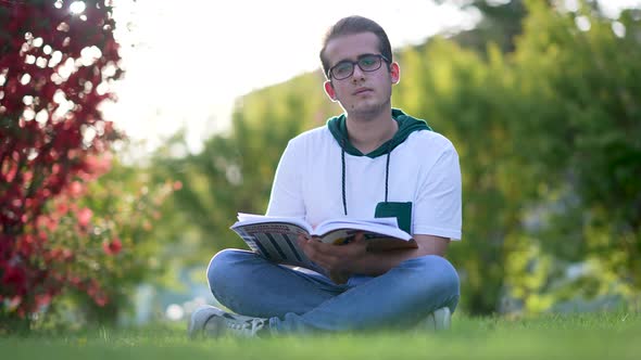 University student sitting on grass, writing essay, literary studies project alt
