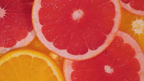 Citrus Fruit Slices  Grapefruit and Orange on Slow Rotating Surface Close Up