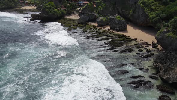 Aerial view of tropical beach in Gunung kidul, Indonesia with green and rocky cliff. alt
