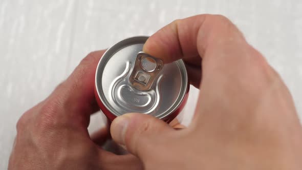 Male opening unmarked soda can of fizzy cola close up