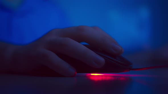 Close-up of a man's hand presses the buttons of a computer mouse, evening light alt