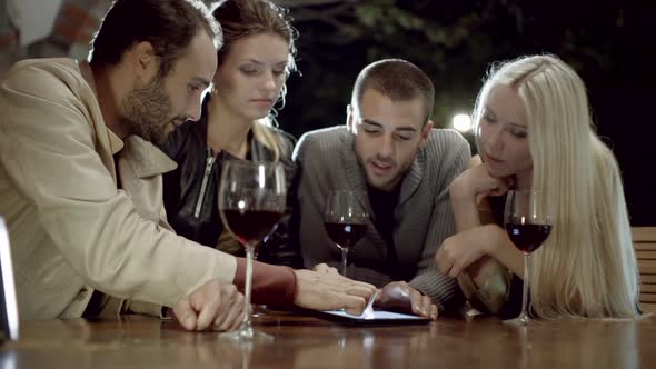 Group of Friends Uses Tablet While Drinks Wine in Rural Farm House Tuscany Italy at Night Slow alt