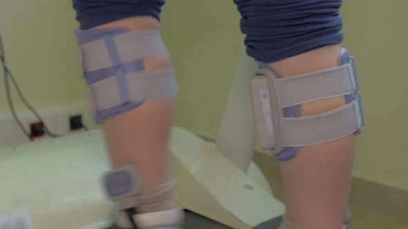 Child exercising on treadmill with electrical stimulation on legs alt