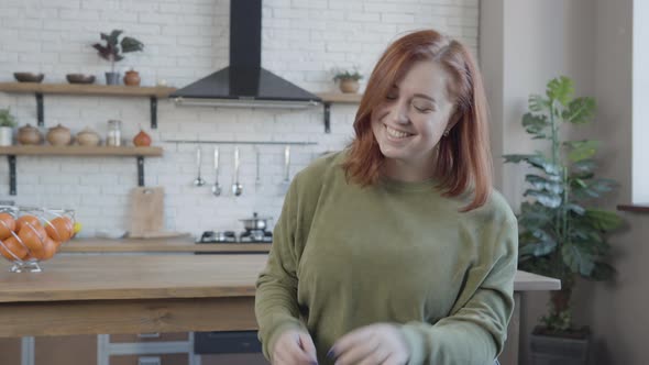 Portrait of Positive Plussize Woman Sitting in Kitchen Smiling at Camera alt