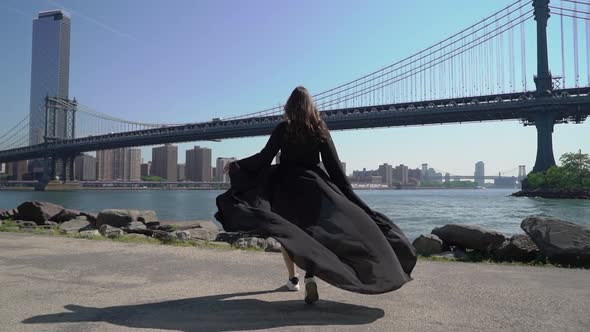 Young Woman in Black Long Dress Walks Near Manhattan Bridge in New York USA
