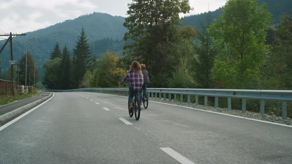 Couple Riders Cycling Mountains Together on Highway Road alt
