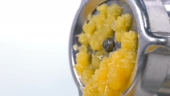 Orange Is Scrolled Through a Meat Grinder and It Comes Out in Small Pieces Through Holes and Juice alt