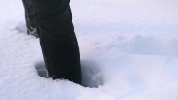 A Man in Boots Walks Through Snowdrifts