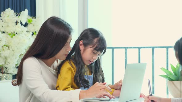 Asian single mother teaching homework to her little sibling daughter child alt