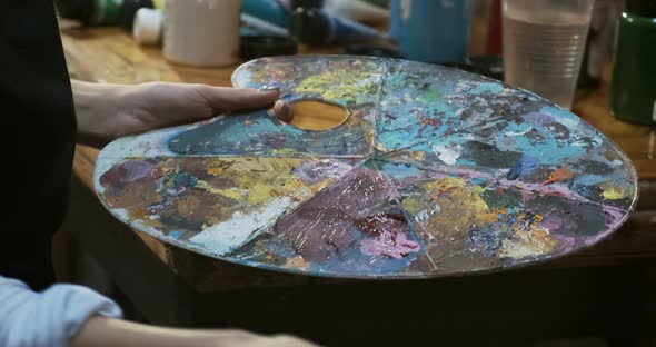 Close Up of Woman Hand Mixing Oil Paints on Wooden Palette. Attractive Girl Creates Modern Art alt