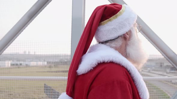 Santa Claus walking around the city during sunset. Big city. Pedestrian walkway.