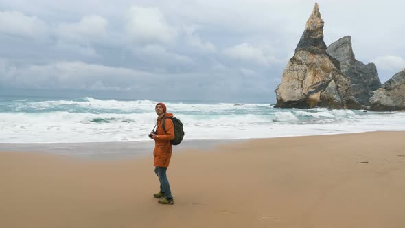 Happy Man with Large Backpack Walks Along Empty Ocean Beach alt