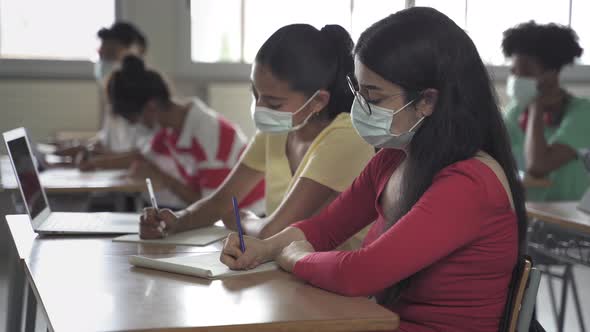 Secondary School Students Wearing Medical Face Masks Writing Notes During Class at the High School alt