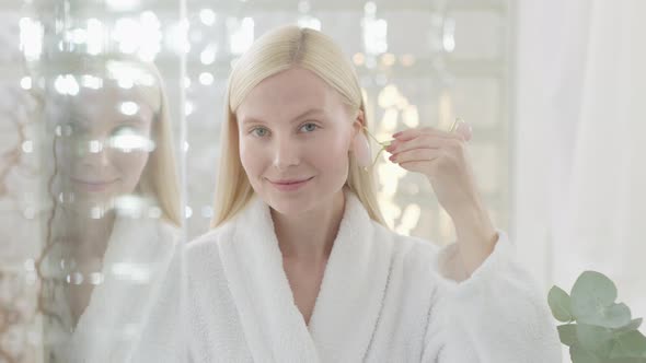 Pretty Female Doing Facial Massage in Bright Bathroom alt