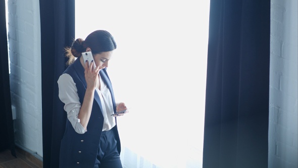 Businesswoman on cellphone talking while using the other