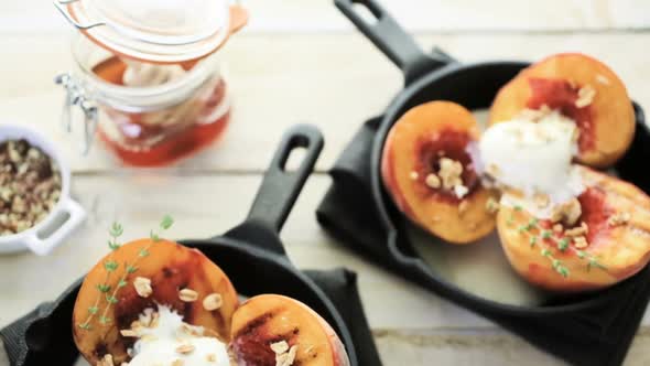 Organic grilled peaches with scoop of vanilla ice cream on a cast iron frying pan. alt