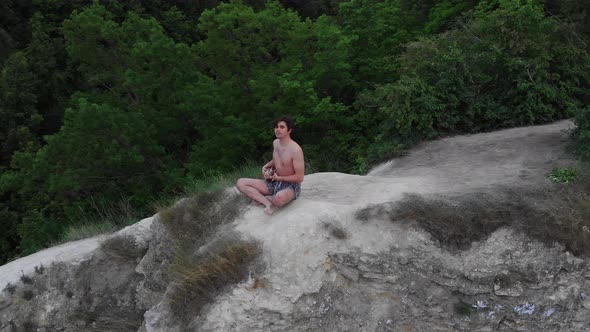 Young Shirtless Man Playing Ukulele on the Cliff alt
