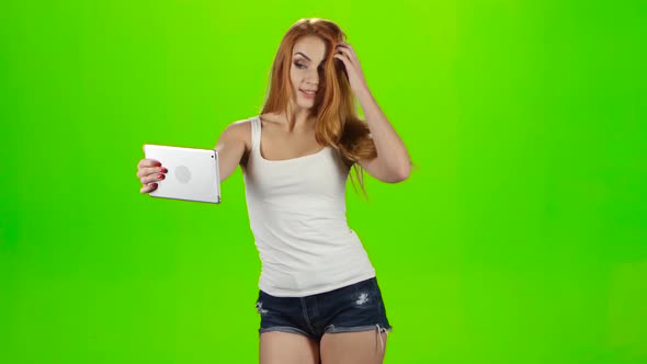 Redheaded Girl Model Makes Selfie on the Tablet, Green Screen alt