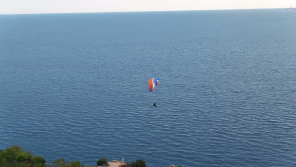 Aerial Following Paragliders Over Sea With View Of Mountains And Green alt