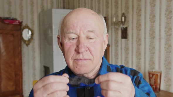 Seniour Caucasian Man Putting on False Moustache Looking at the Camera Enjoying and Smiling Cozy alt