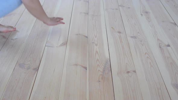 Eco-friendly Flooring - Woman with Bare Feet Strokes the Warm Wooden Floor Closeup