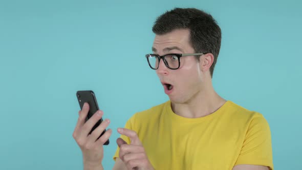 Man Reacting To Loss and Using Smartphone, Blue Background alt