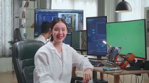 Development Facility:  Asian Woman Smiling To Camera. Female Working On Green Screen Computer alt