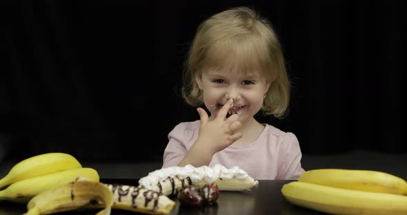 Child Eats Banana, Strawberry with Melted Chocolate and Whipped Cream alt