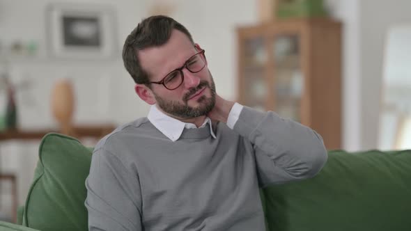 Middle Aged Man Having Neck Pain on Sofa alt