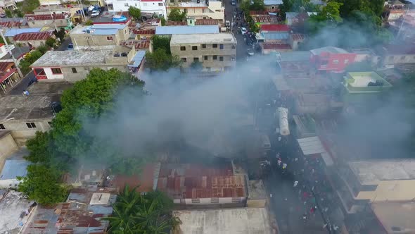 Aerial view around a smoking building, burning on a crowded city street - circling, drone shot alt