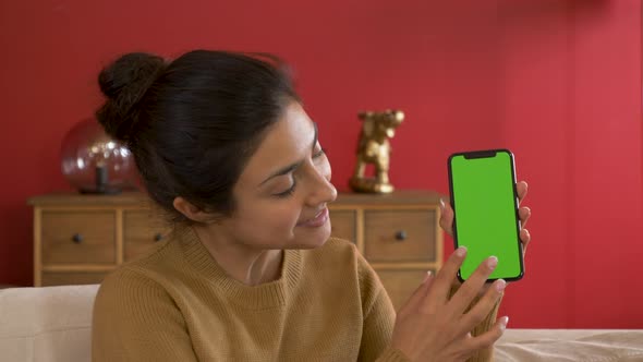 Smiling Young Indian Woman Holds A Smartphone Showing A New App That Uses The Gadget alt