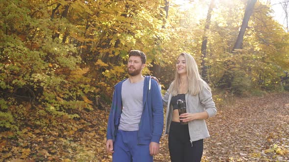 Happy Man and Woman Walking in the Autumn Forest After a Run in the Fresh Air, a Young Couple Loves alt