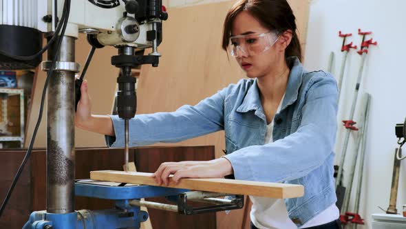 Asian carpenter student woman drill wood by drilling  machine in university wood workshop
