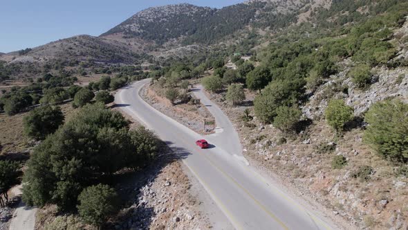 Drone Aerial view red car drive in beautiful mountainous terrain. Small cars driving alt