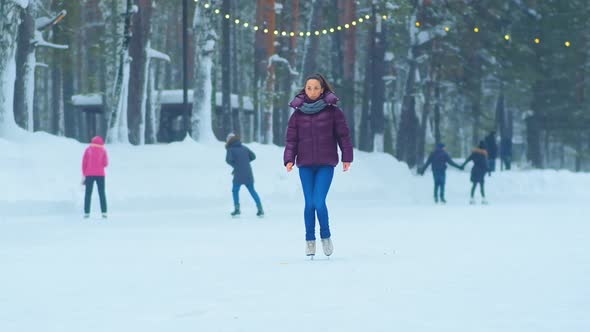 Woman in Jacket Stands on Ice of Outdoor Park Skating Rink