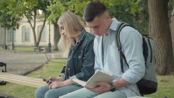 Side View Portrait of Focused Young Male Student Reading Book As Relaxed Caucasian Girl Dancing To alt